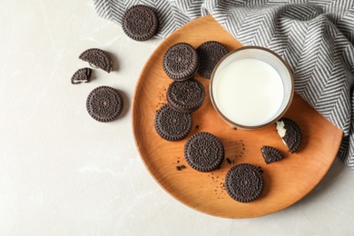 Photo of Plate with chocolate sandwich cookies and milk on light background, top view. Space for text