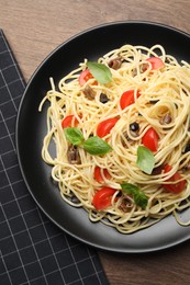 Photo of Delicious pasta with anchovies, tomatoes and basil on wooden table, top view
