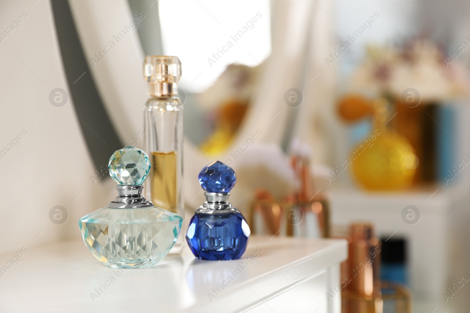 Photo of Bottles of perfumes on dressing table in stylish room interior