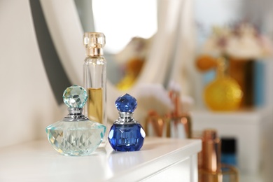 Photo of Bottles of perfumes on dressing table in stylish room interior