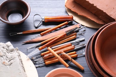Photo of Clay, dishes and set of crafting tools on black table