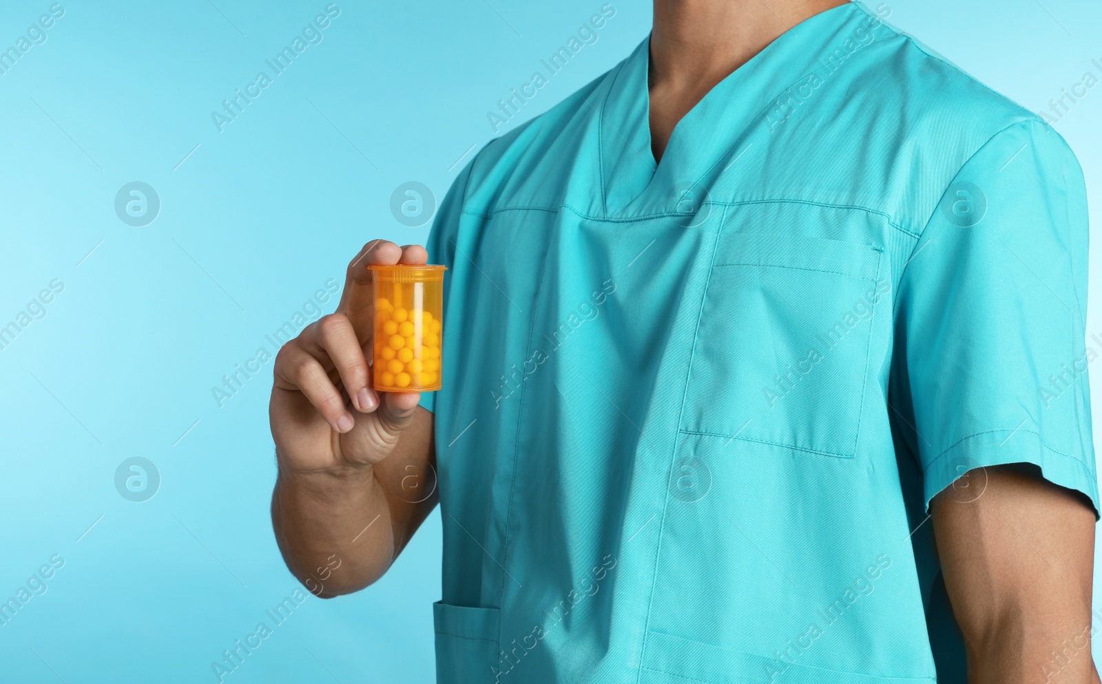 Photo of Male doctor holding pill bottle on color background, closeup. Medical object