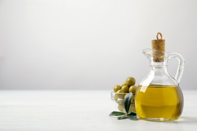 Photo of Bottle of fresh olive oil on white table, space for text