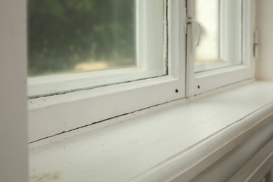 Photo of Old window with white wooden sill in room, closeup