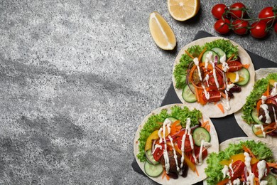 Photo of Many delicious vegetarian tacos served on grey table, flat lay. Space for text