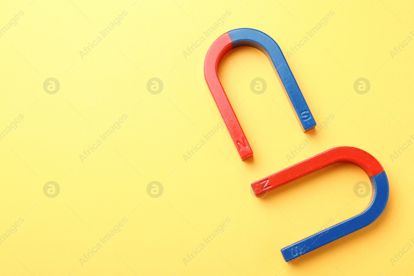 Photo of Red and blue horseshoe magnets on color background, top view with space for text