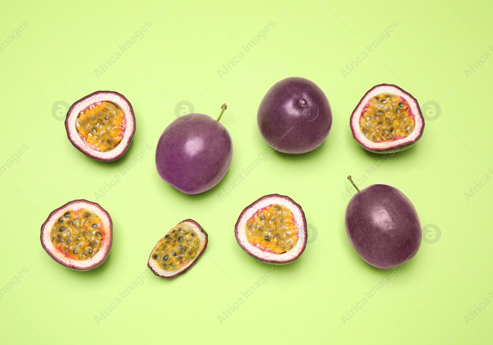 Photo of Fresh ripe passion fruits (maracuyas) on light green background, flat lay