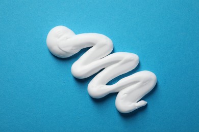 Photo of Sample of shaving foam on blue background, top view