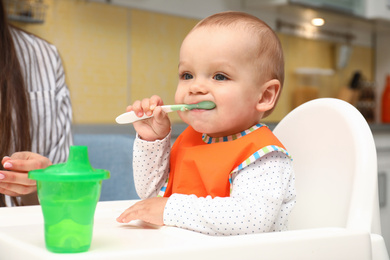 Young mother feeding her little baby at home