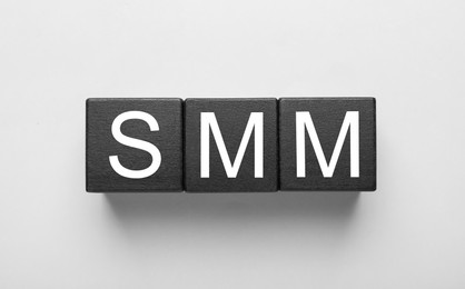 Photo of Cubes with abbreviation SMM (Social media marketing) on white background, top view