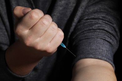 Addicted man with syringe taking drugs, closeup