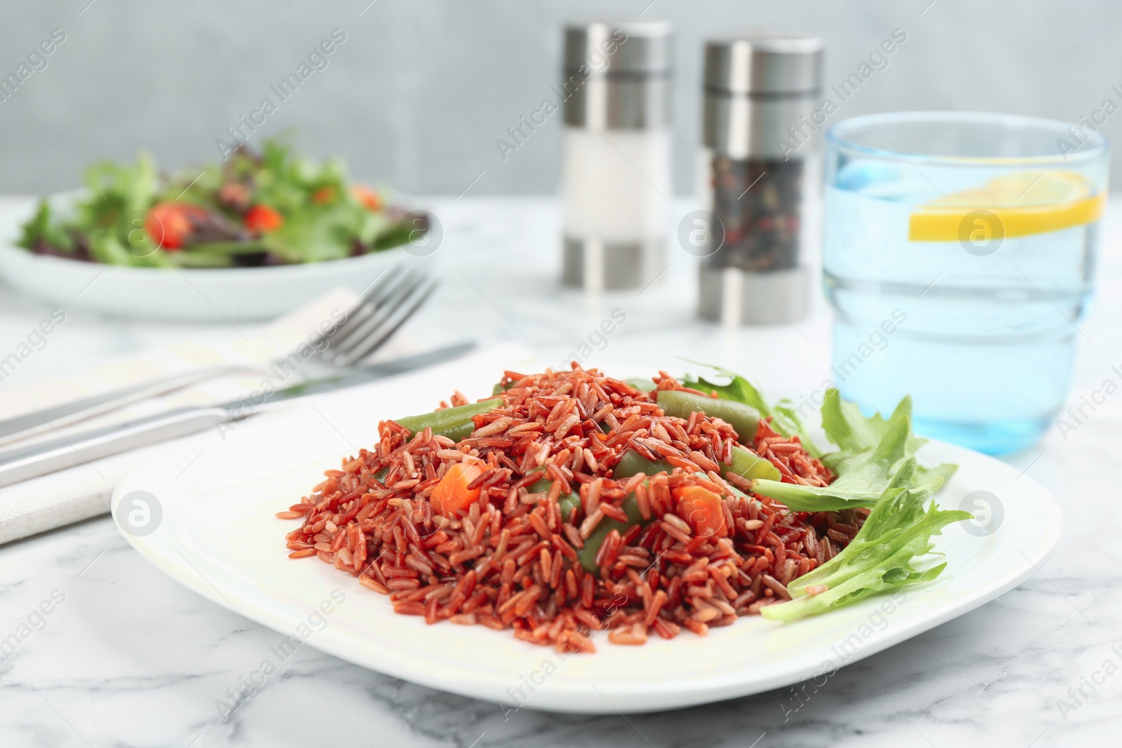 Photo of Tasty brown rice with vegetables on white marble table