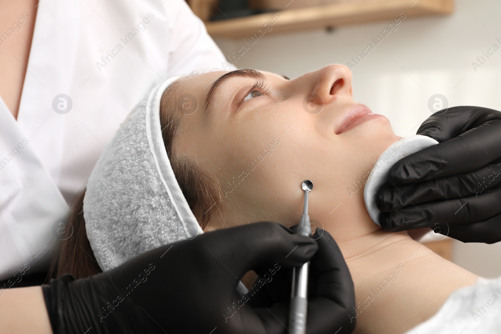 Photo of Cosmetologist using scrubber, closeup. Client having cleansing procedure