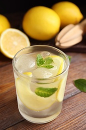 Cool freshly made lemonade in glass on wooden table, closeup