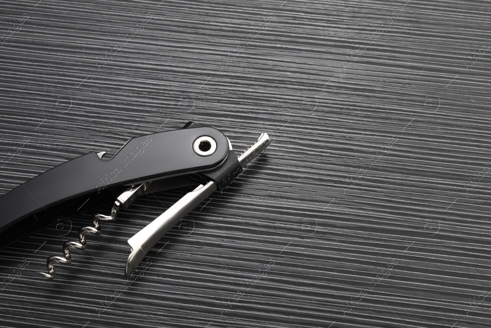 Photo of One corkscrew (sommelier knife) on black wooden table, top view. Space for text