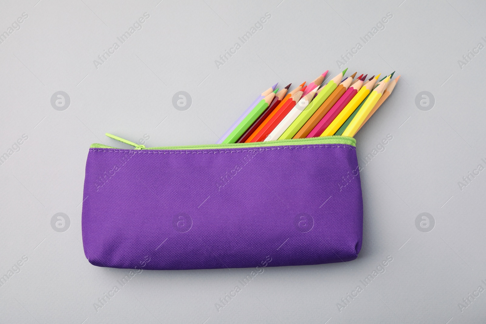 Photo of Many colorful pencils in pencil case on light grey background, top view