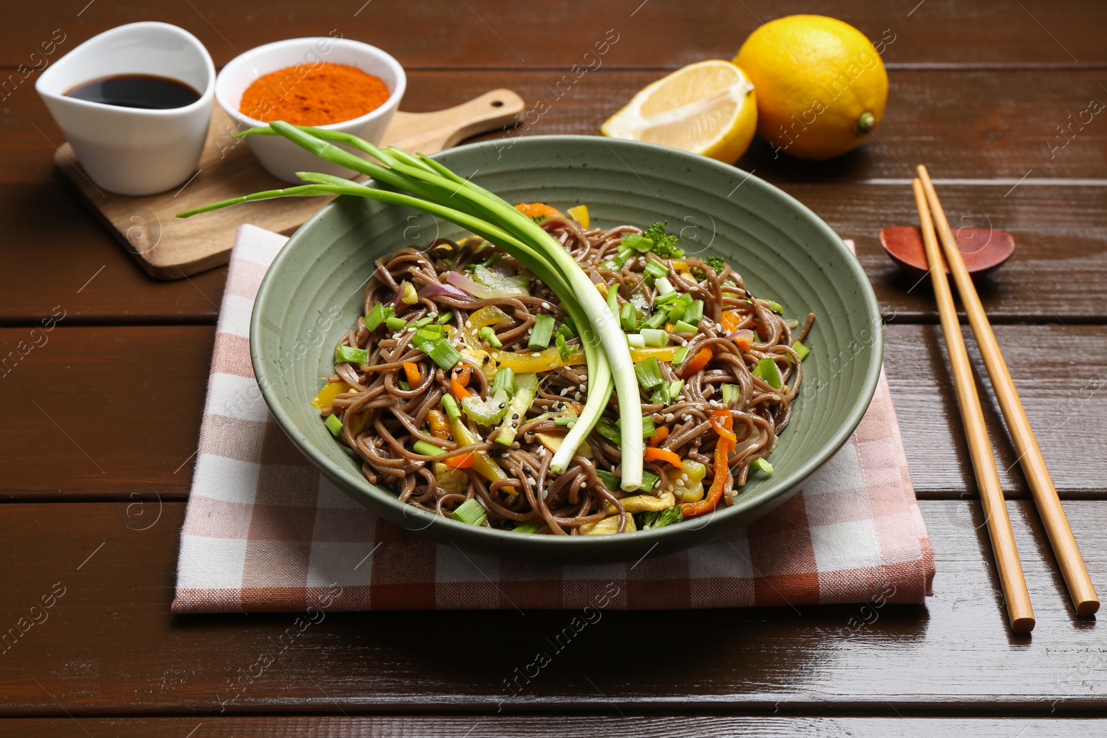 Photo of Stir-fry. Delicious cooked noodles with chicken and vegetables in bowl on wooden table