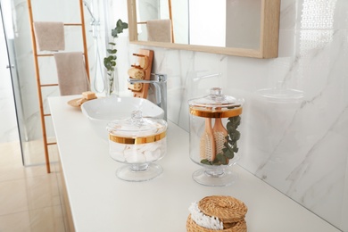 Jars with cotton pads and hairbrushes on bathroom countertop