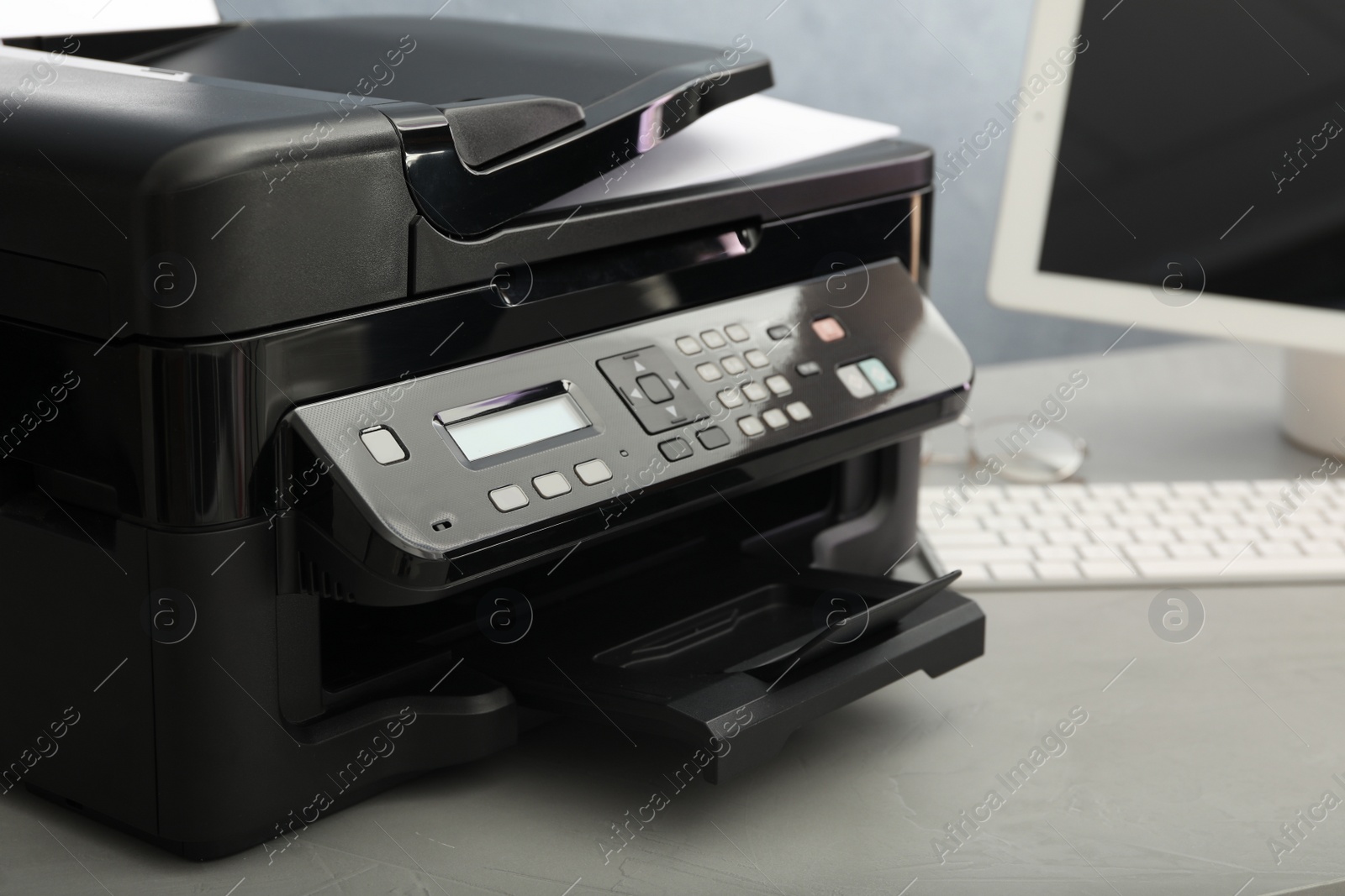 Photo of Modern printer with paper on grey table, closeup