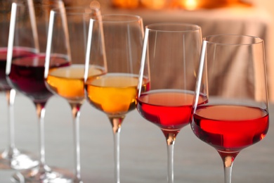 Row of glasses with different wines against blurred background, closeup