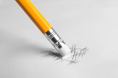 Photo of Erasing scribbles with graphite pencil on white background, closeup