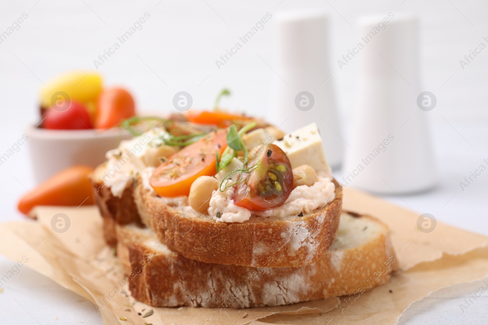 Photo of Tasty vegan sandwich with tomatoes, tofu and chickpeas on white table, closeup