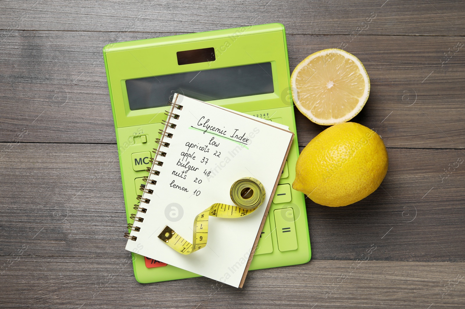 Photo of Notebook with products of low glycemic index, calculator, measuring tape and lemons on wooden table, flat lay