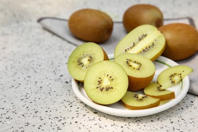 Photo of Whole and cut fresh kiwis on white table with pattern. Space for text