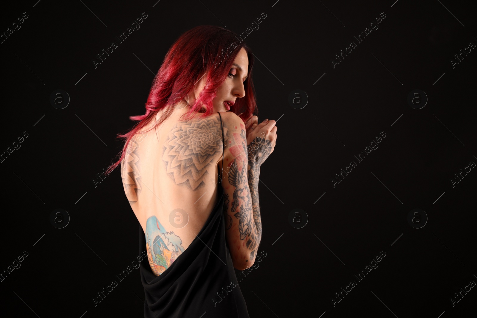 Photo of Beautiful woman with tattoos on body against black background