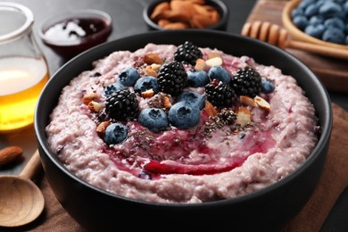 Photo of Tasty oatmeal porridge with toppings in bowl served on table, closeup