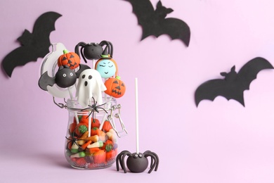 Photo of Delicious Halloween themed cake pops on pink background. Space for text
