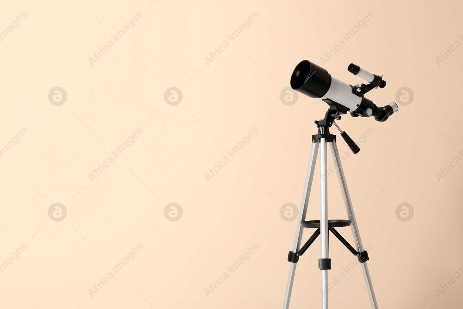 Photo of Tripod with modern telescope on beige background. Space for text