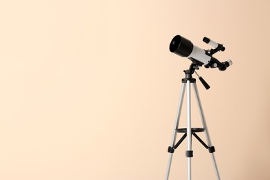 Photo of Tripod with modern telescope on beige background. Space for text