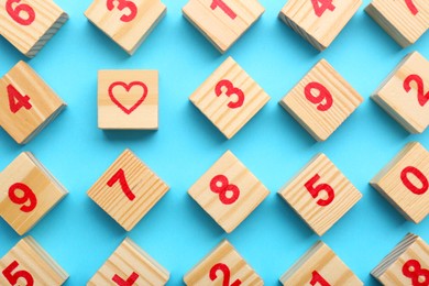 Photo of Wooden cubes with numbers and heart on light blue background, flat lay