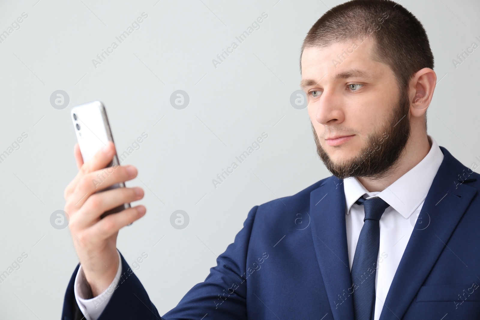 Photo of Man unlocking smartphone with facial scanner on light background. Biometric verification