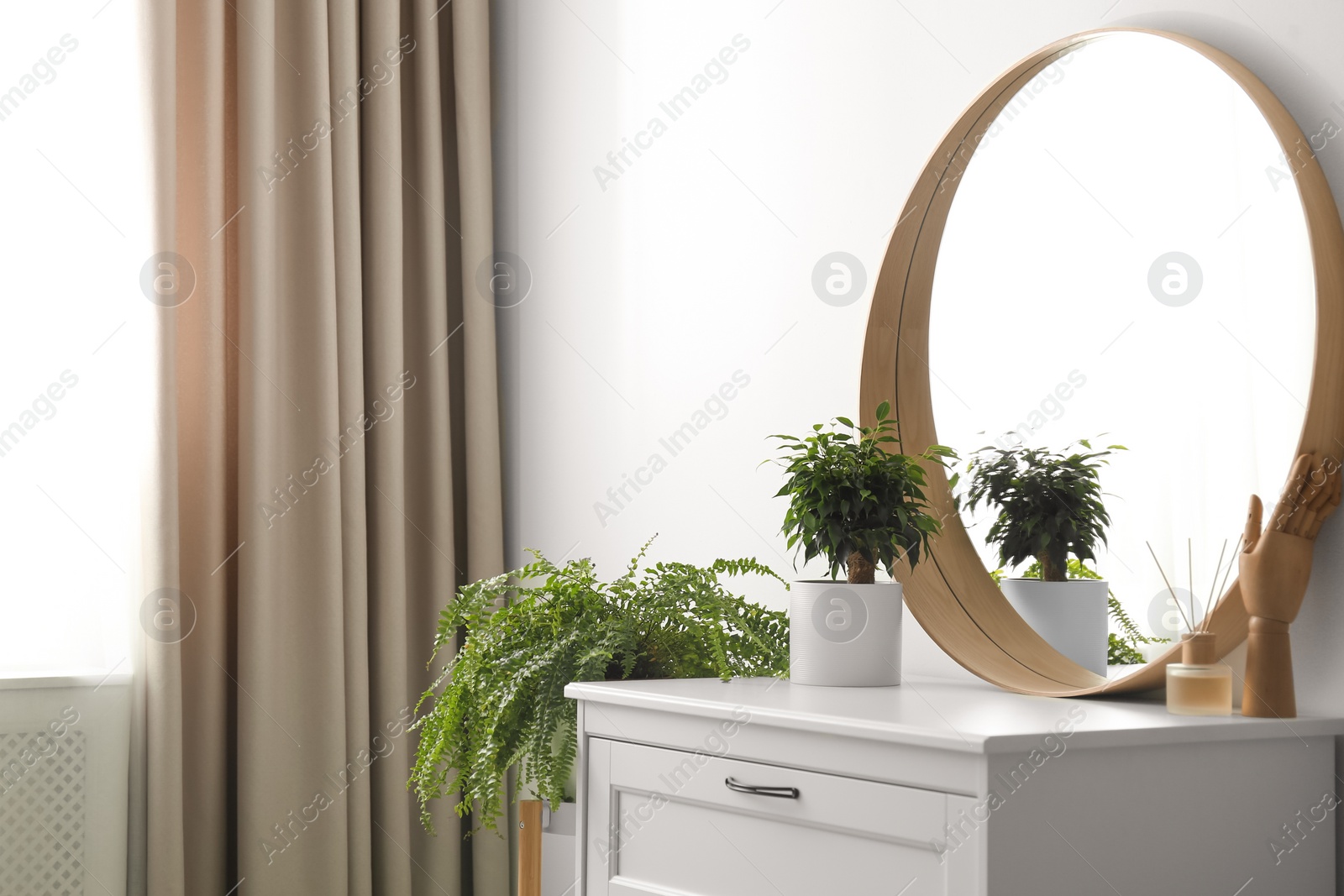 Photo of Round mirror and chest of drawers near white wall in room. Modern interior design