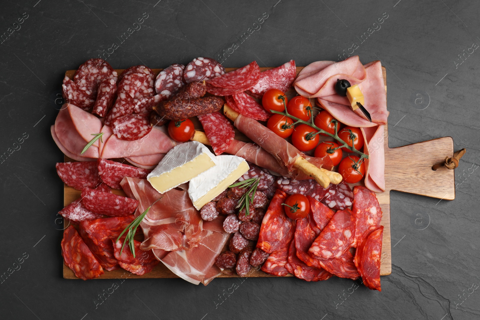 Photo of Tasty ham and other delicacies served on black table, top view