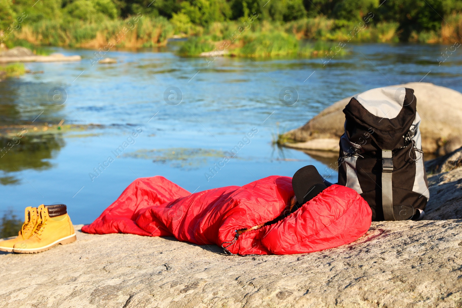 Photo of Woman resting in sleeping bag near lake on sunny day