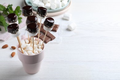 Photo of Delicious marshmallows covered with chocolate on white wooden table. Space for text