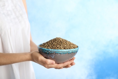 Photo of Woman holding bowl with hemp seeds on color background, closeup