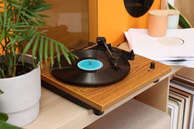Stylish turntable with vinyl record on console table indoors