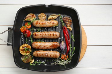 Photo of Grill pan with tasty sausages and vegetables on white wooden table, top view