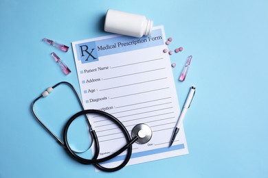 Photo of Medical prescription form, stethoscope, ampoules and pills on light blue background