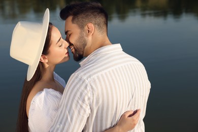 Photo of Romantic date. Beautiful couple kissing near lake