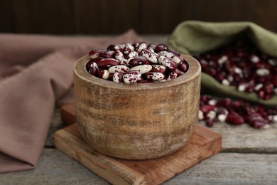 Photo of Bowl with dry kidney beans on old wooden table, closeup