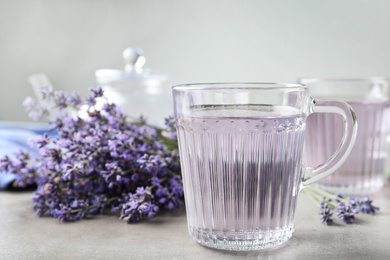 Photo of Fresh delicious drink with lavender in glass cup on grey table