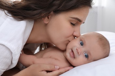 Photo of Happy young mother with her cute baby on bed at home, closeup