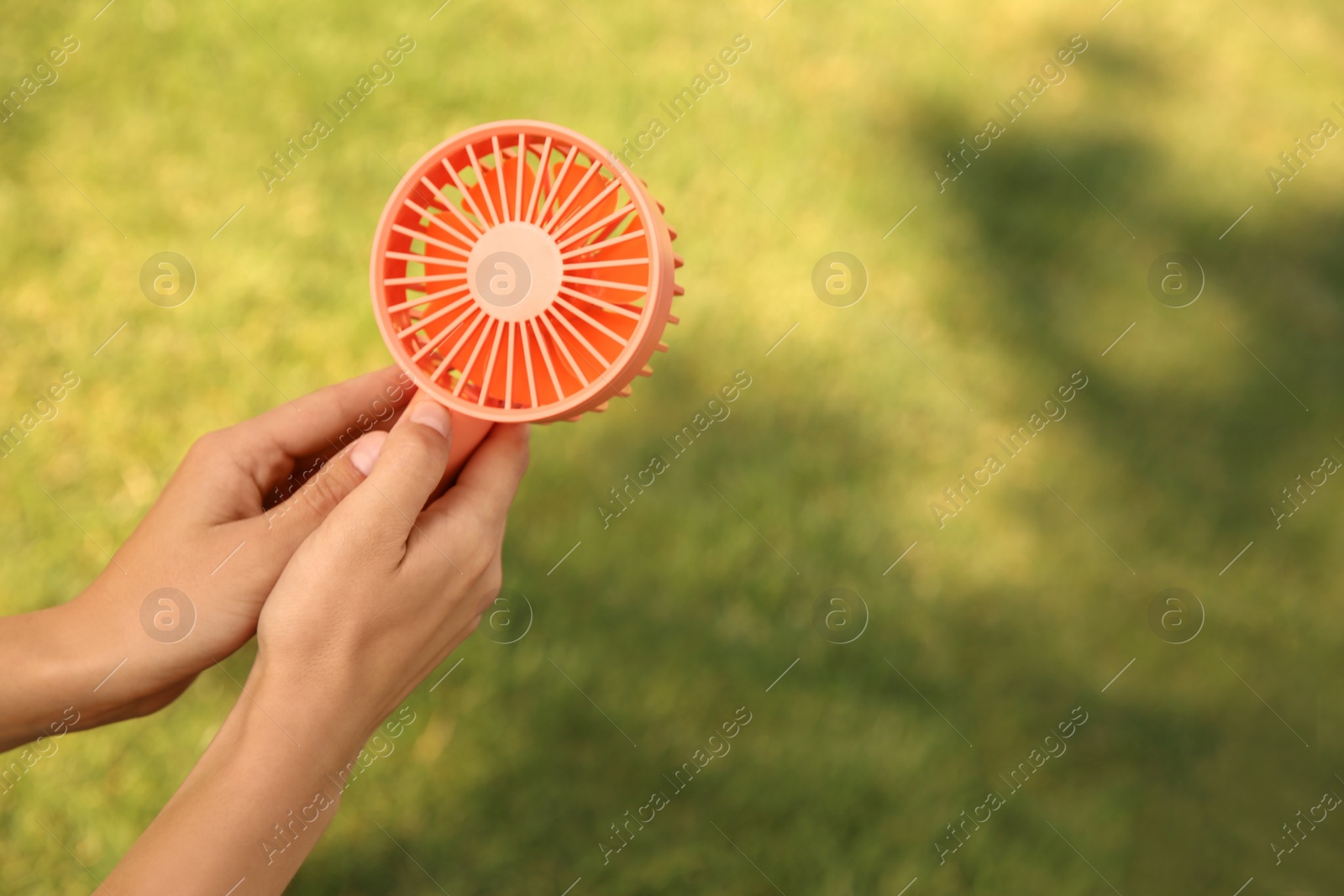 Photo of Woman holding portable fan outdoors on sunny summer day, closeup. Space for text