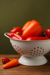 Photo of Colander with fresh vegetables on wooden table