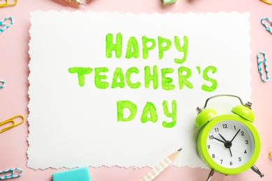 Photo of Paper with inscription HAPPY TEACHER'S DAY and alarm clock on color background